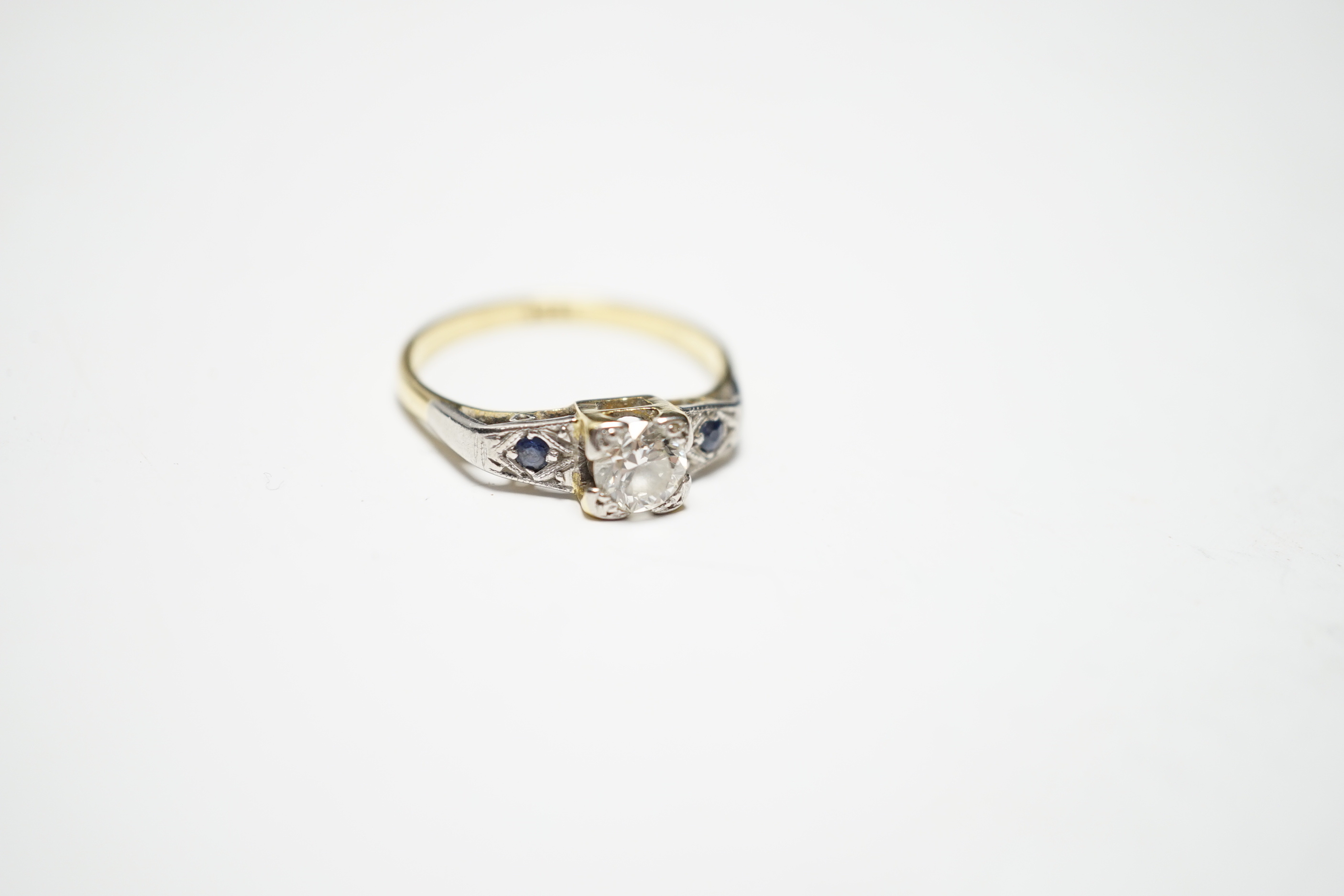 An 18ct and single stone diamond ring, with sapphire set shoulders, size N, gross weight 3.6 grams.